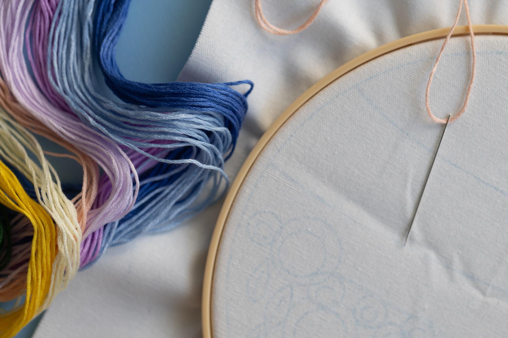 Close-up of hand embroidery on linen with pastel threads
